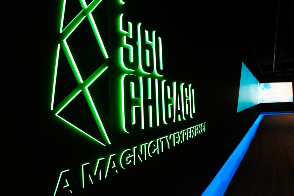 360 CHICAGO welcome experience, 875 North Michigan Avenue, Chicago — illuminated 360 CHICAGO sign with green LED edge lighting