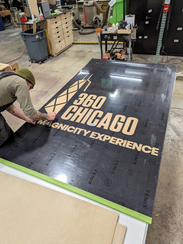 360 CHICAGO welcome experience, 875 North Michigan Avenue, Chicago — installing the 360 CHICAGO floor graphic in the shop