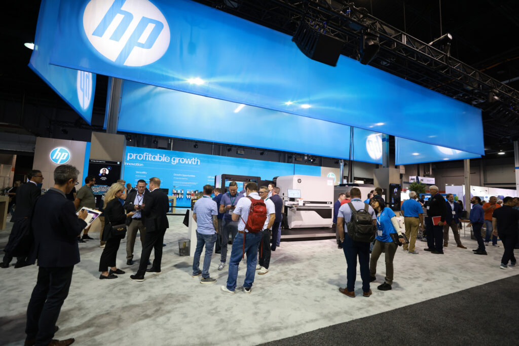 Crowded HP booth at Labelexpo Americas with an overhead HP sign and blue graphic walls