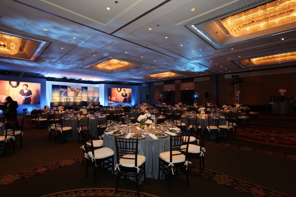Ballroom set for the Diageo Believe general session dinner with stage and screens