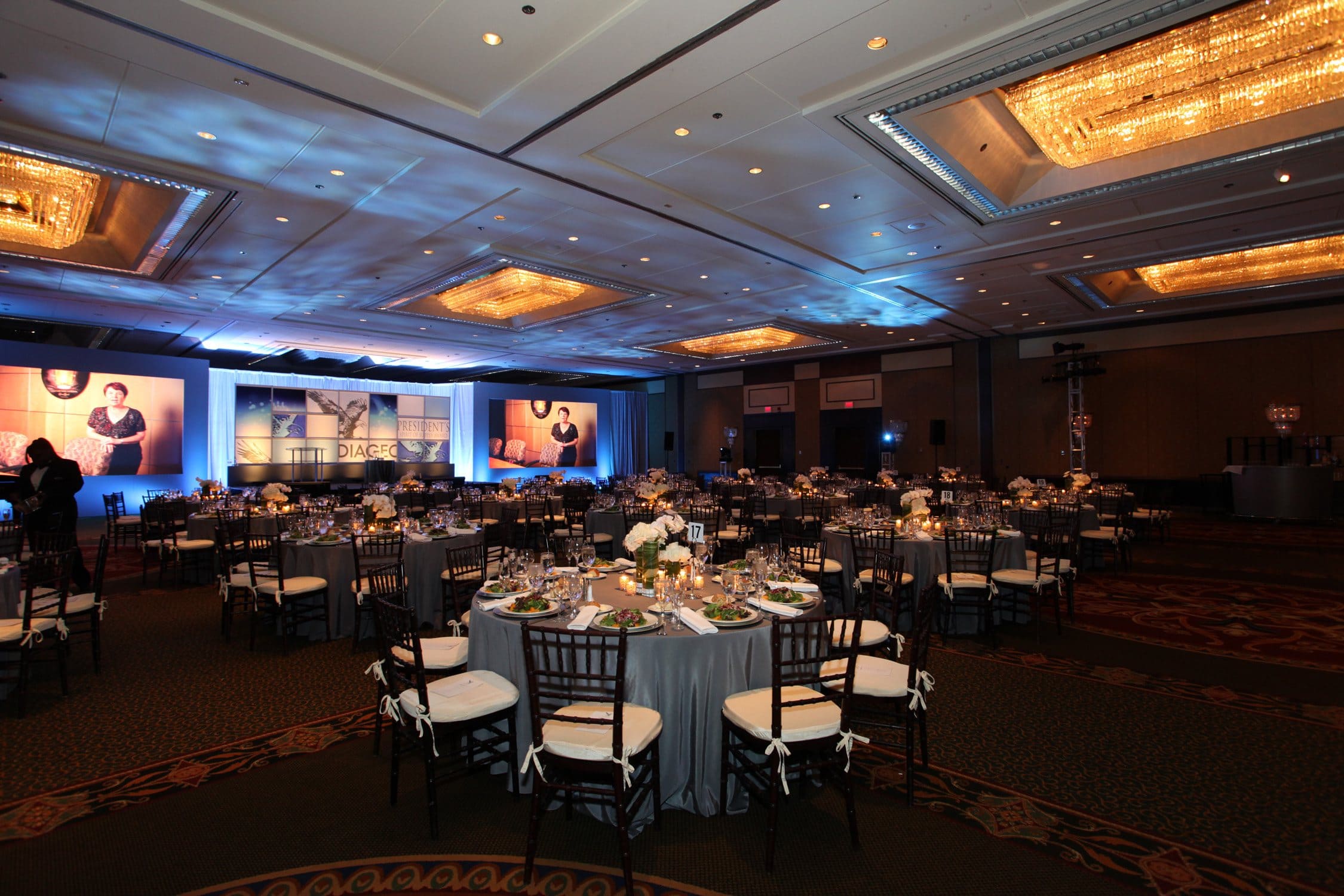 Ballroom set for the Diageo Believe general session dinner with stage and screens