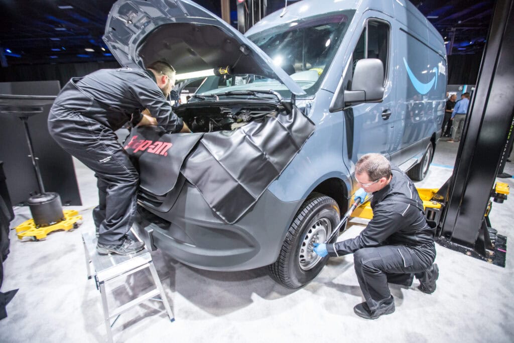 Technicians demonstrating service work on a van at a live demo station