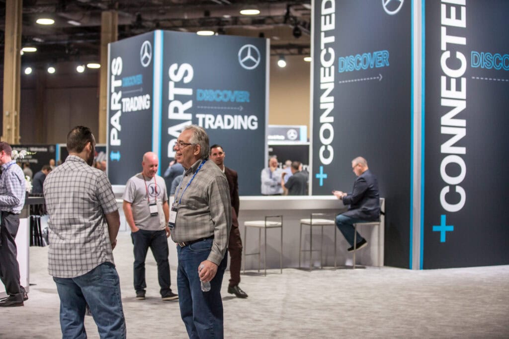 Exhibitors and attendees talking at a custom parts booth