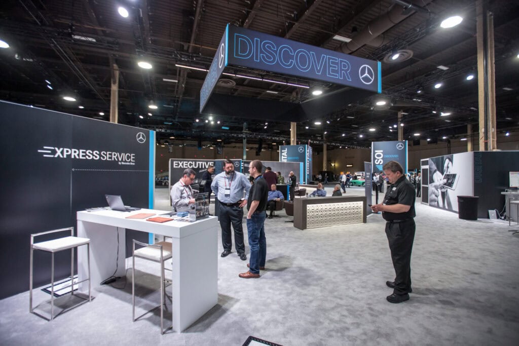 Exhibitor booth with custom counter and overhead sign on a private show floor